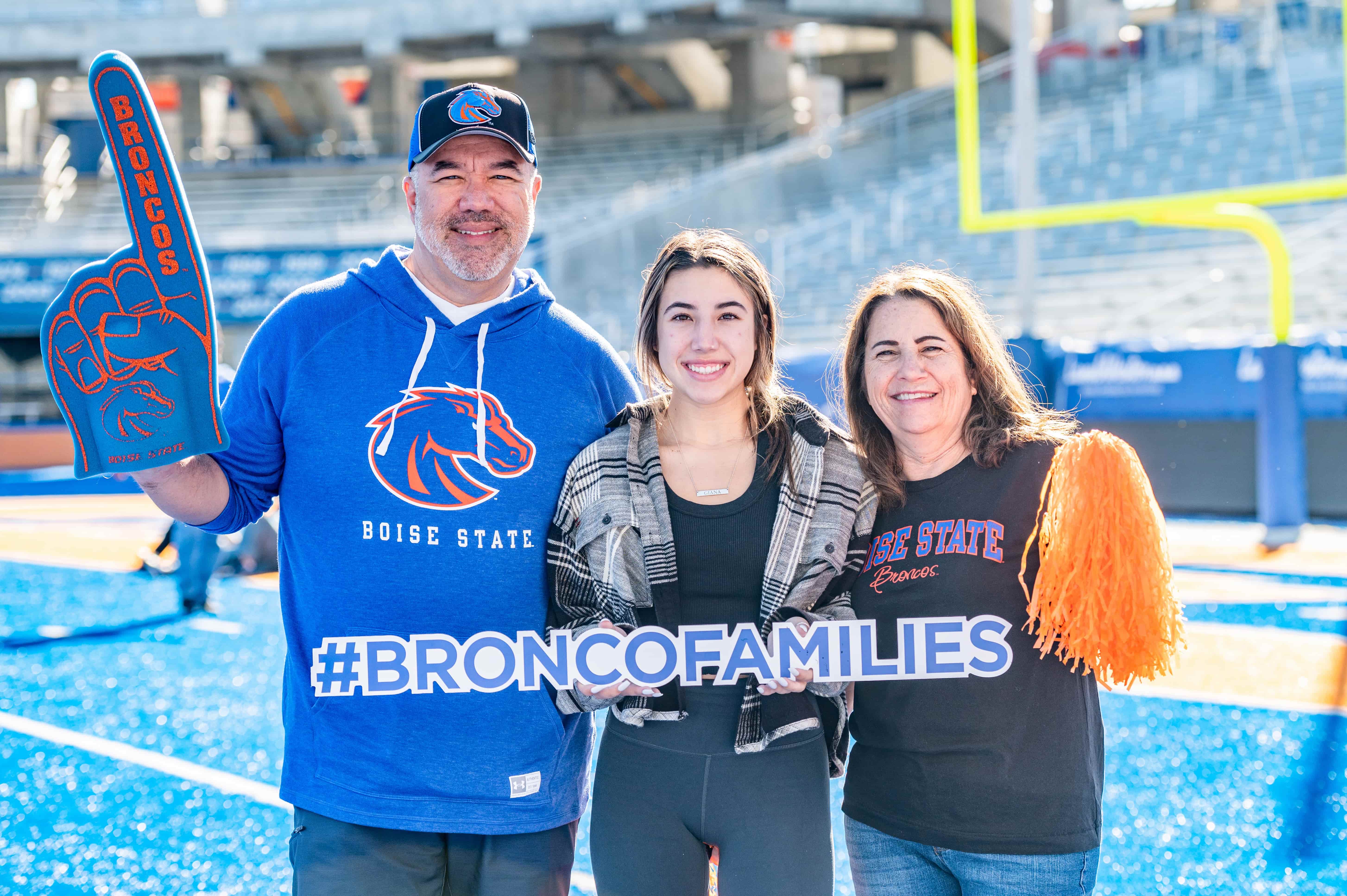 BSU student standing on blue turf with parents