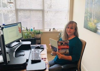 Director Dana Thorp Patterson at her work-from-home desk, holding an Osher Institute catalog