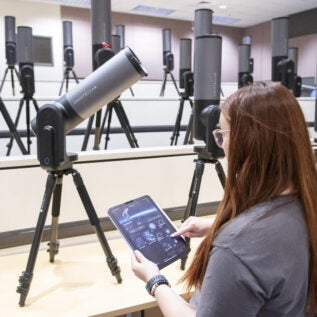Woman controlling telescope with tablet