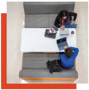 students work on laptops at a large table