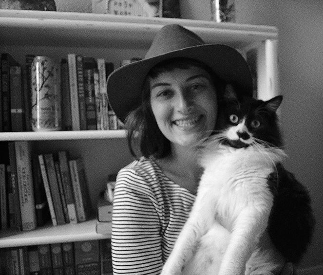 Morgan Ackley smiles while wearing a hat and holding her cat