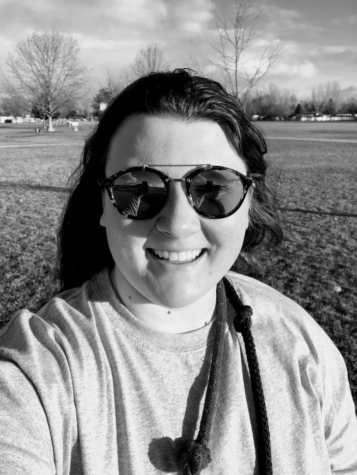 The author takes a selfie in the park while smiling and wearing sunglasses.