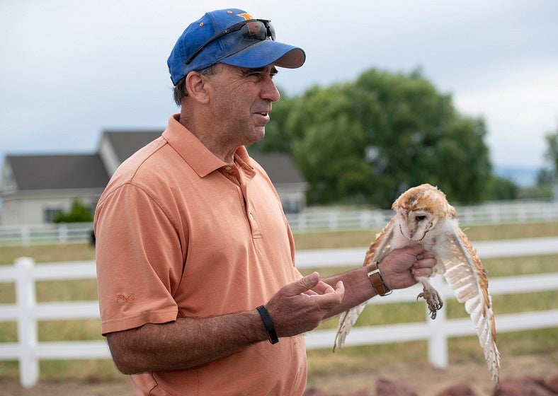 Jim Belthoff holding a Barn Owl outside a farm