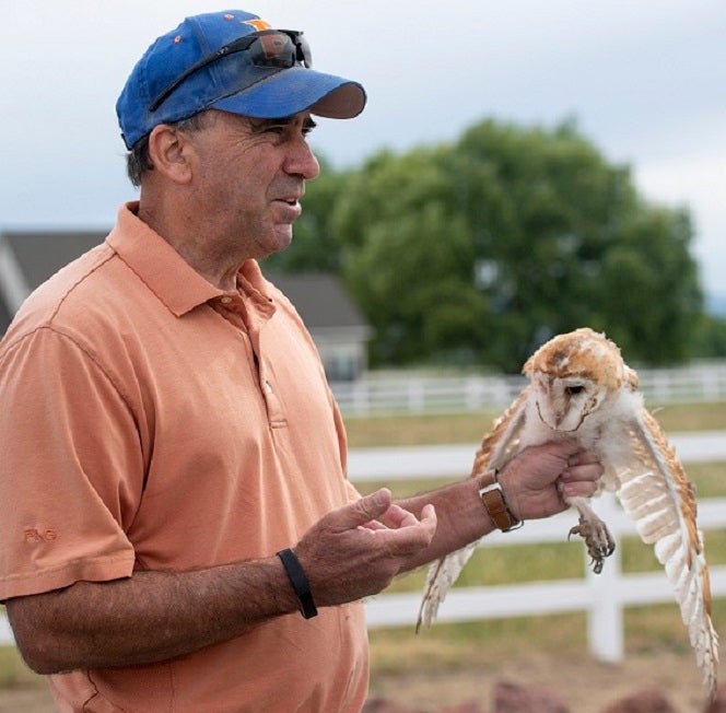 Jim Belthoff holding a Barn Owl outside a farm