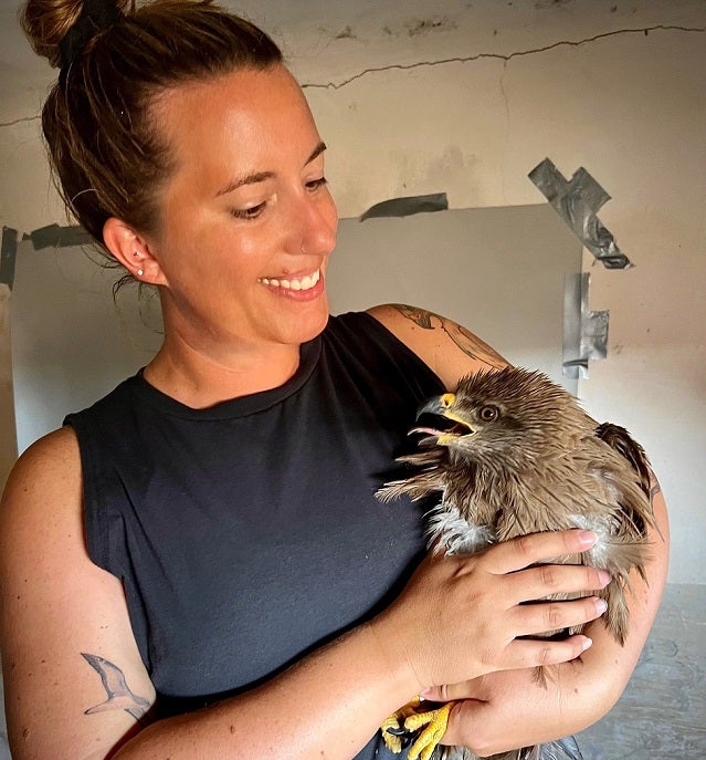 IRES student holding black kite at trapping station after taking measurements