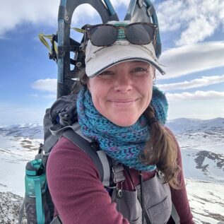 Portrait of professor Stephanie Galla with pack and snowshoes in arctic landscape