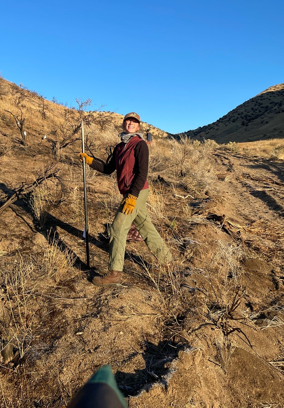 Elle Horwath smiling while hiking up a hill doing fieldwork