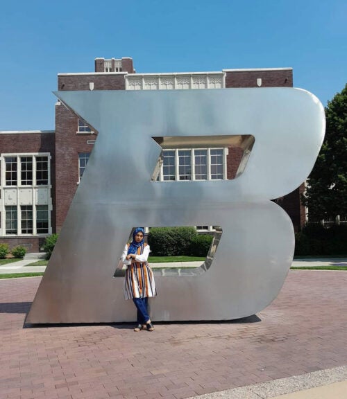 Sabrina Akther posing by the B statue