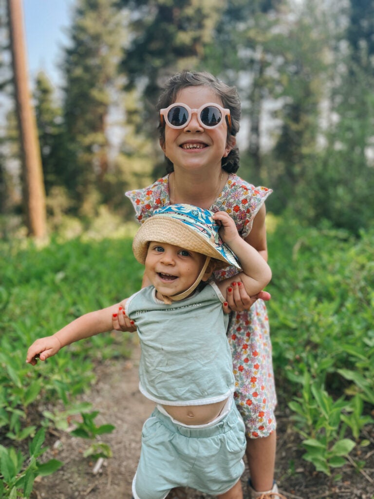 Josie (daughter) lifts Oli (son) to keep him balanced while walking on the forest trail.
