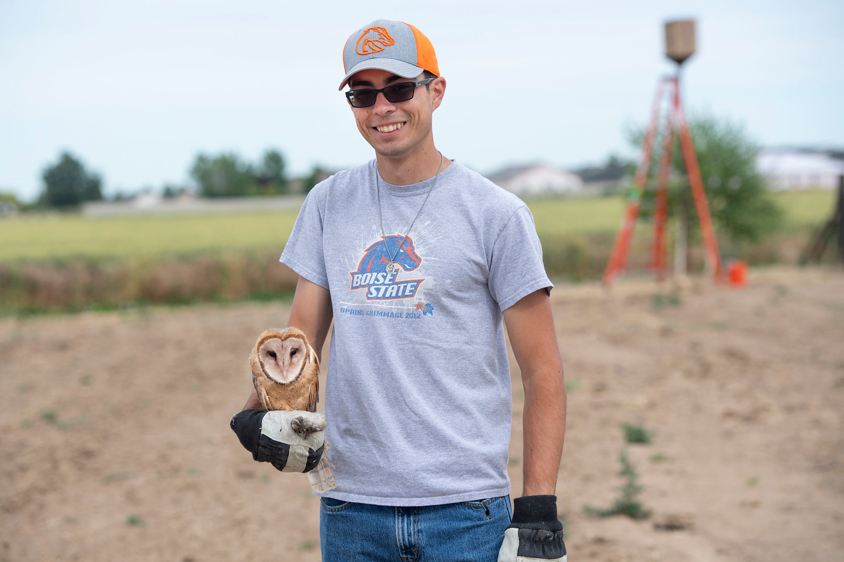 student out at field site holds barn owl in right hand