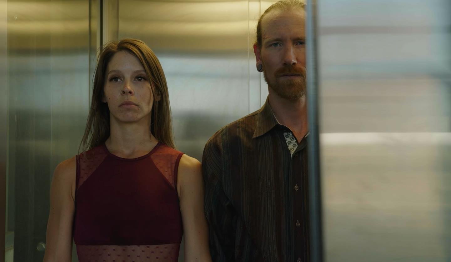 Two people standing in an elevator. Still from Silhouette