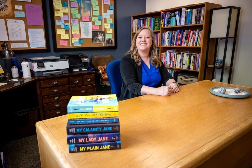 A person sits at a desk with book in the foreground