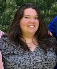 A photo of a white woman with long dark hair smiling