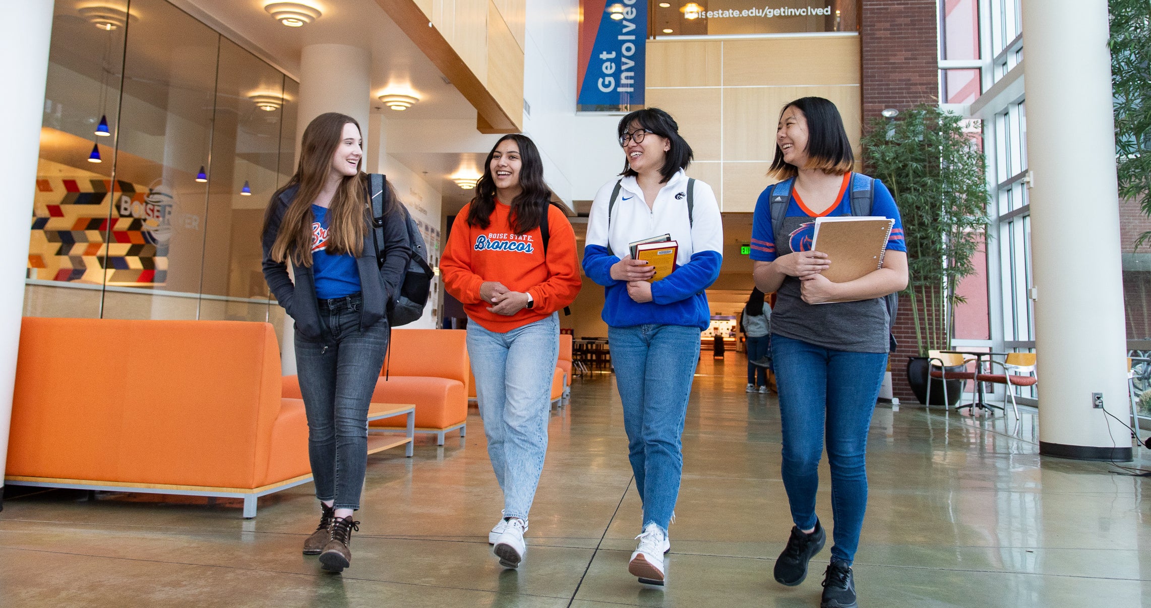 group of 4 students walking and talking on campus