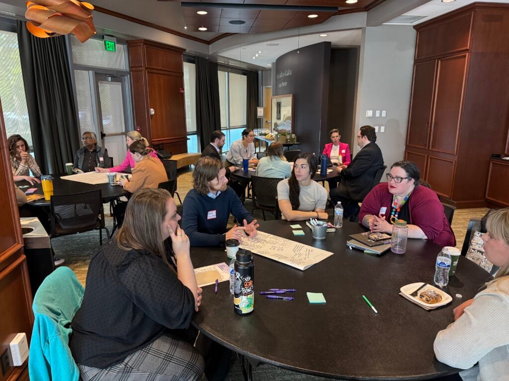 Several people sit around three tables at the UW Convening.