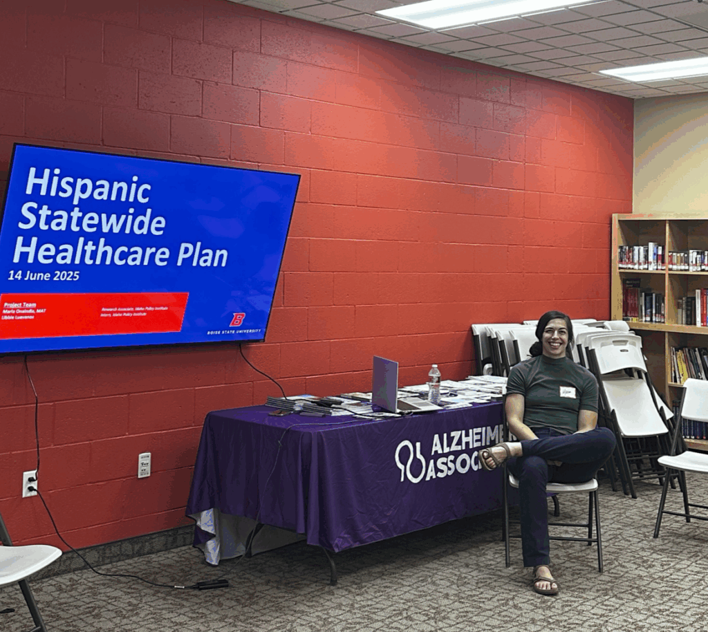 A woman, Maria Onaindia, sits in front of screen that reads "Hispanic Statewide Healthcare Plan."
