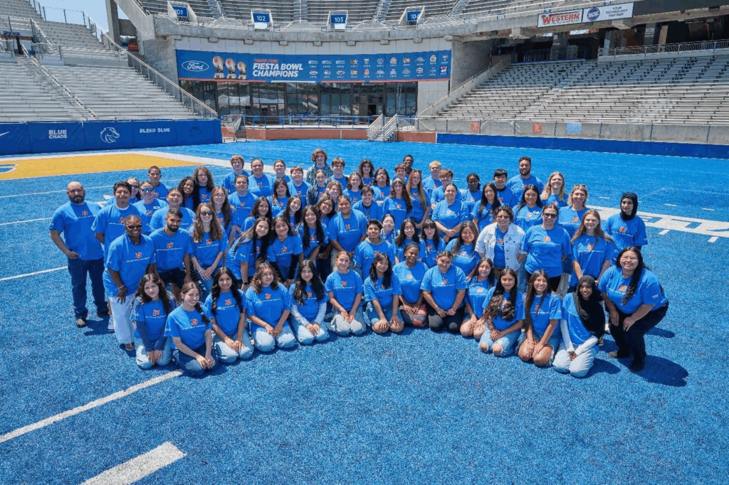 A group of high school students poses on Boise State's blue football turf.