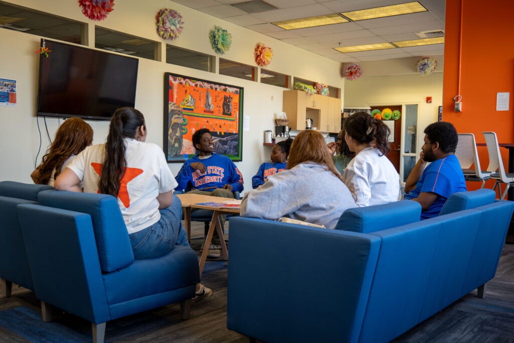 A group of students sitting in the Student Connections and Support Center lounge in a circle.