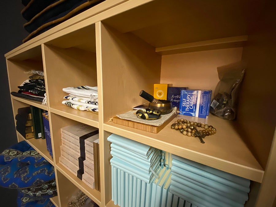 Shelf with books, rosary, prayer mats, meditation cards