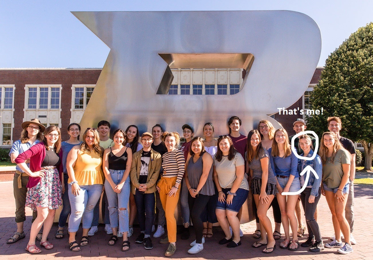 A company newspaper group photo with 22 students by the metal B outside Boise State