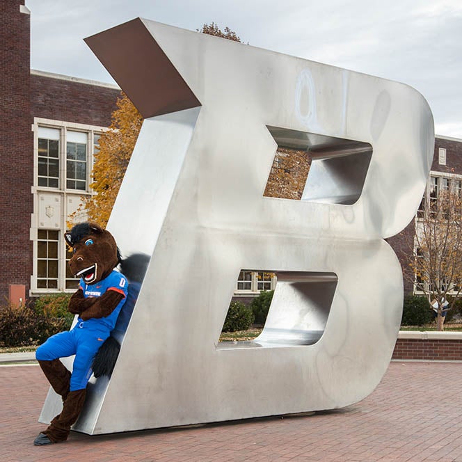 Buster Bronco leaning against the center 'B' in front of the Administration Building