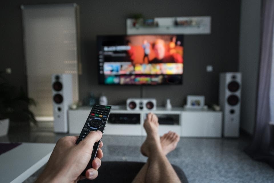 A person sitting on a couch clicks a tv remote.