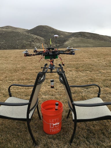 Quadcopter prototype in the field, attached to lawn chairs