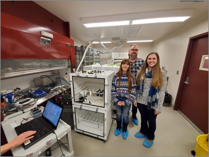 Researchers standing in lab next to equipment