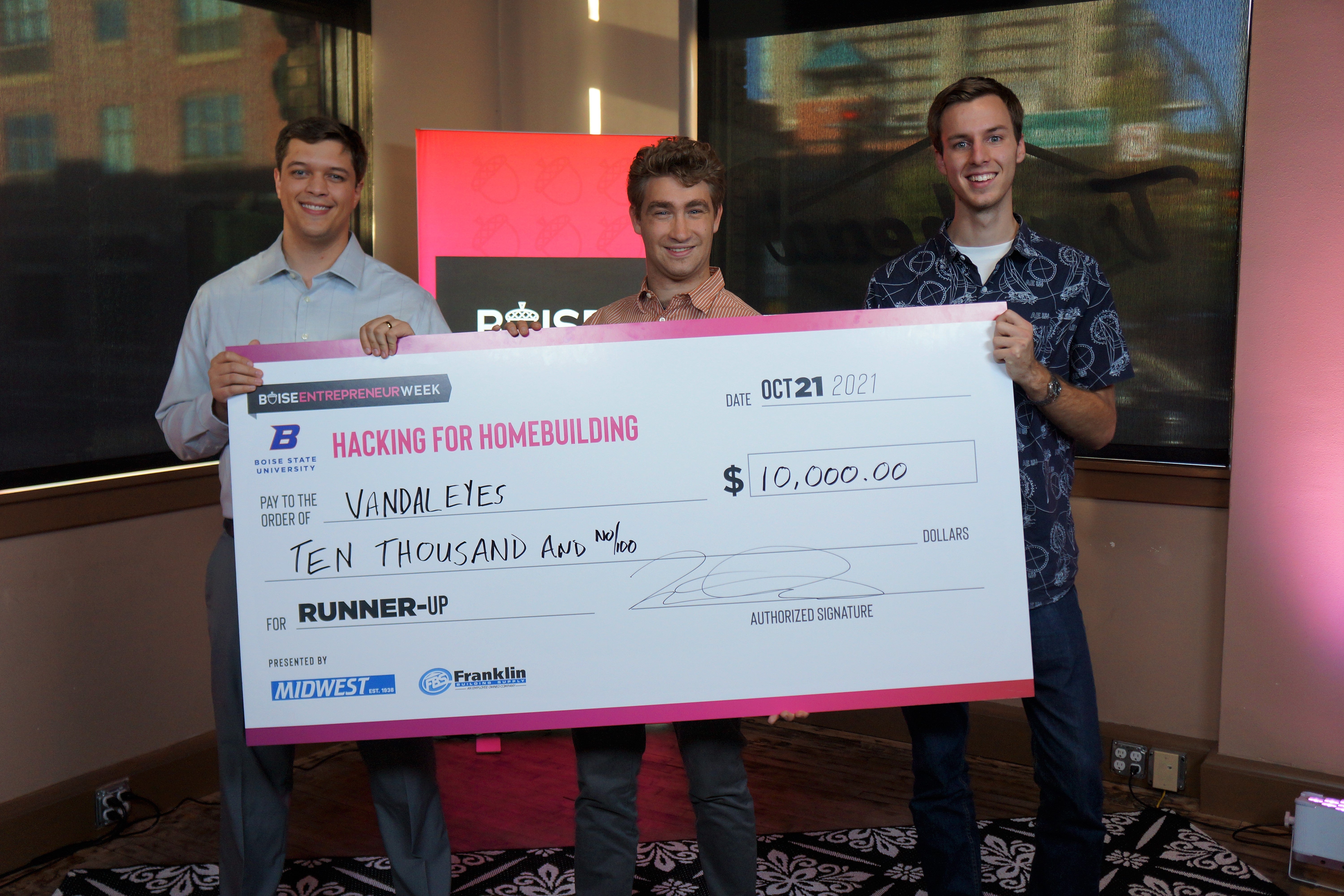 Three students hold a large check for $10,000. 