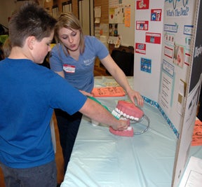 Nursing student teaches student about proper technique for brushing teeth