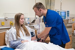 Shelby Gibbons acts as a standardized patient while Nursing student Justin Eaton takes her blood pressure