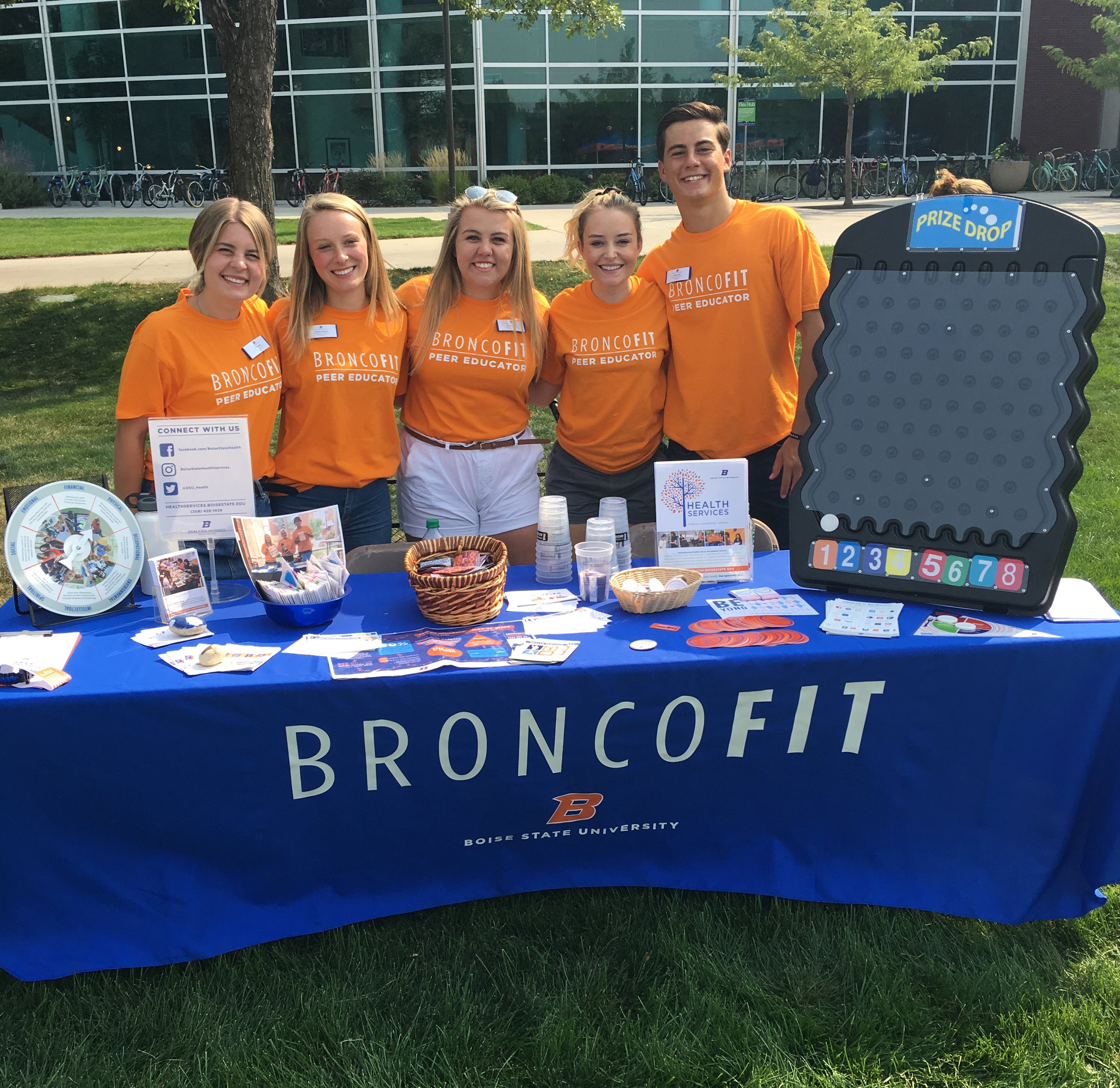 Peer Educators standing infront of table that reads BroncoFit