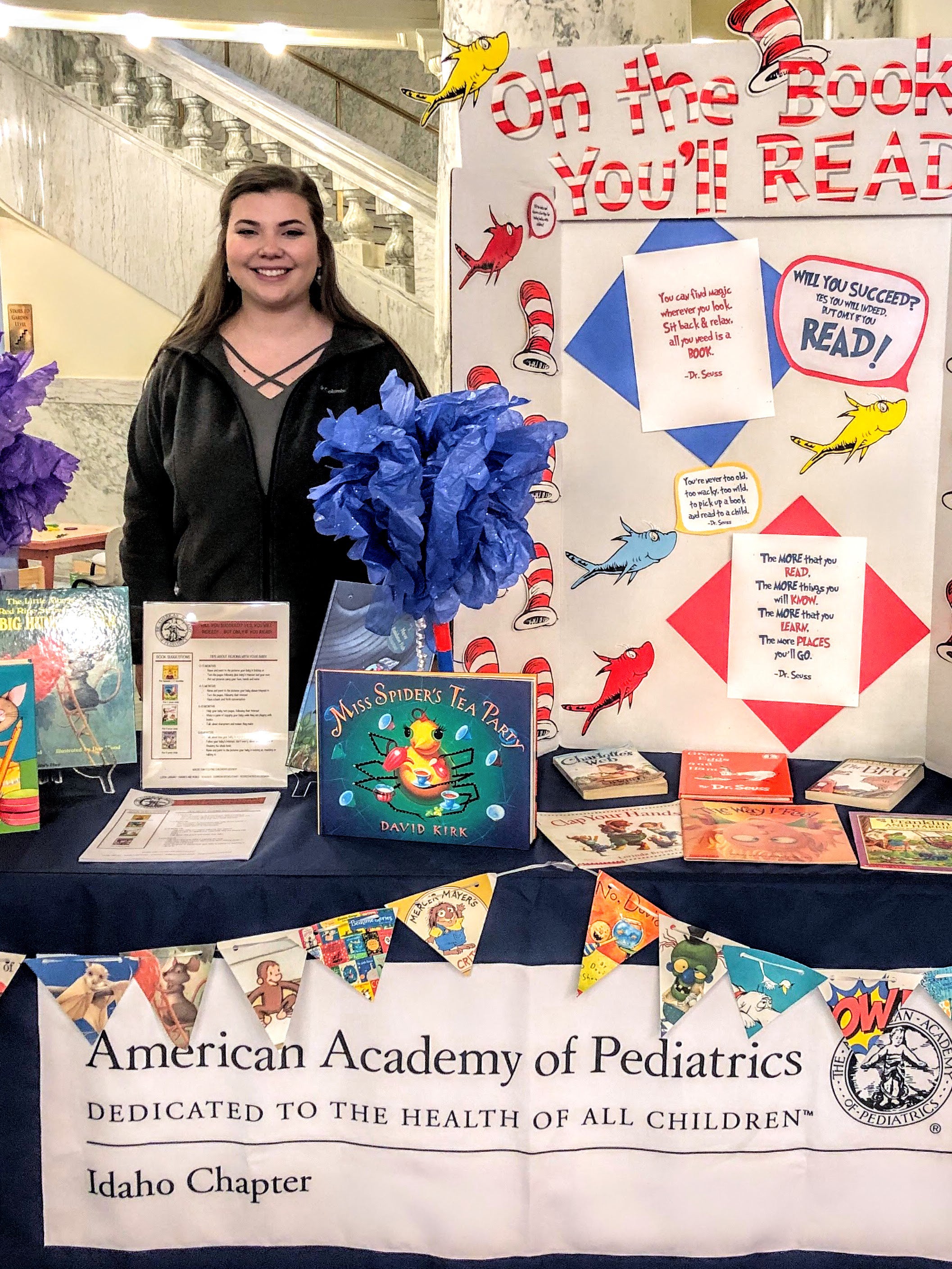 Picture of Dani standing next to a booth made up of her project featuring children's books 