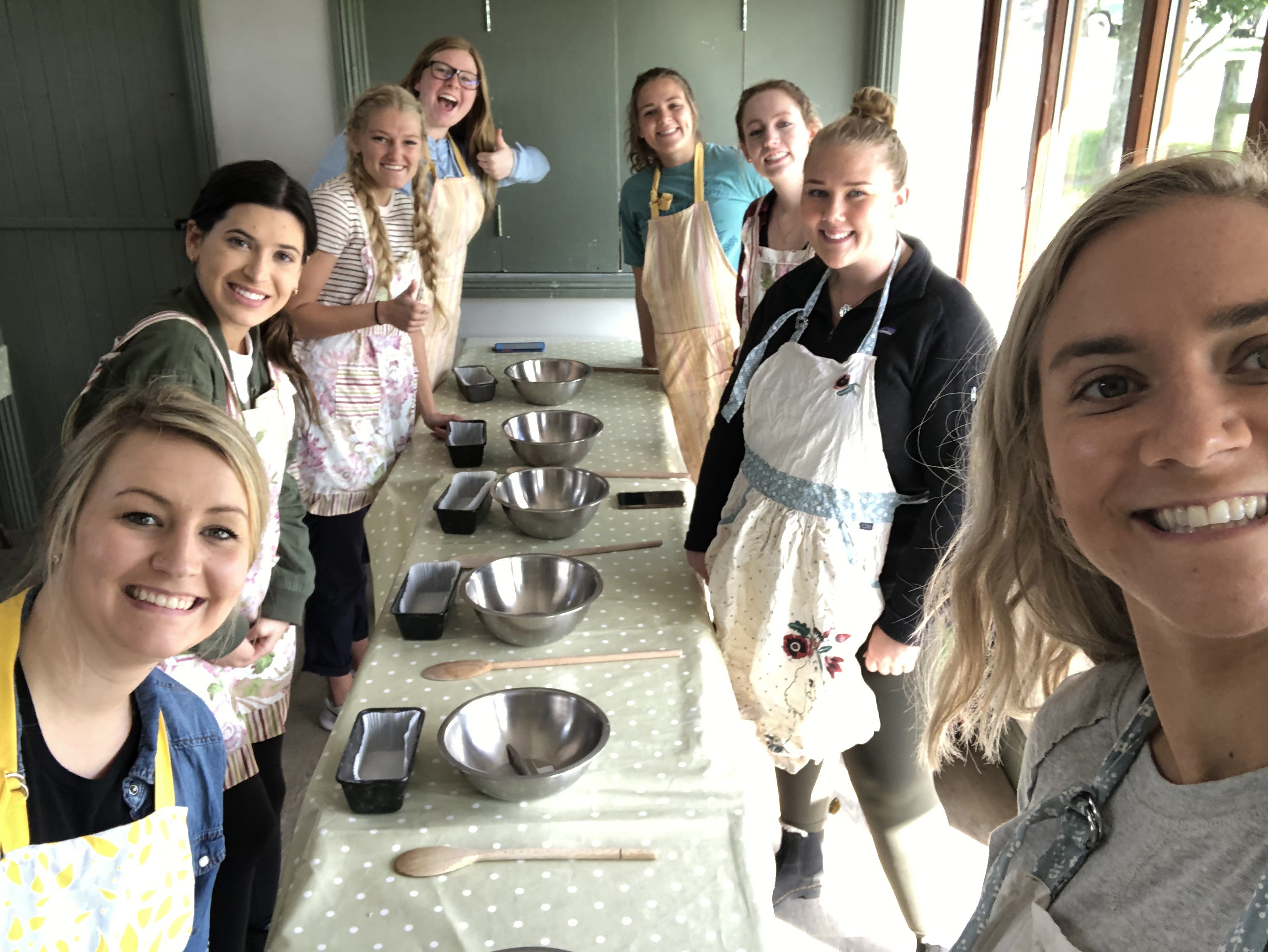 Students posing next to a table while they learn how to make bread