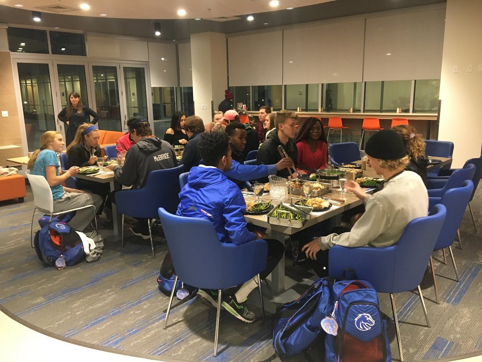 students at two large tables talking and eating dinner