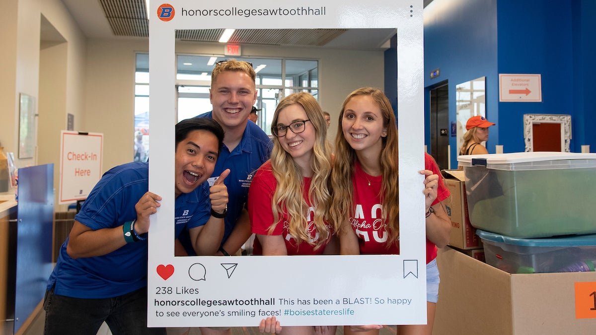 Students hold oversize Instagram frame for Honors College Sawtooth Hall. 