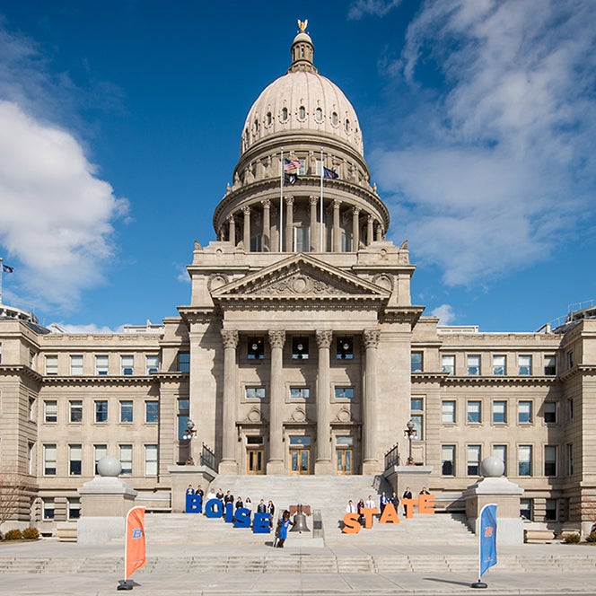 People holding up the letters spelling, "Boise State" in front of the Idaho State Capitol