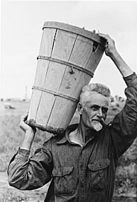 Man carrying large wooden basket on shoulder