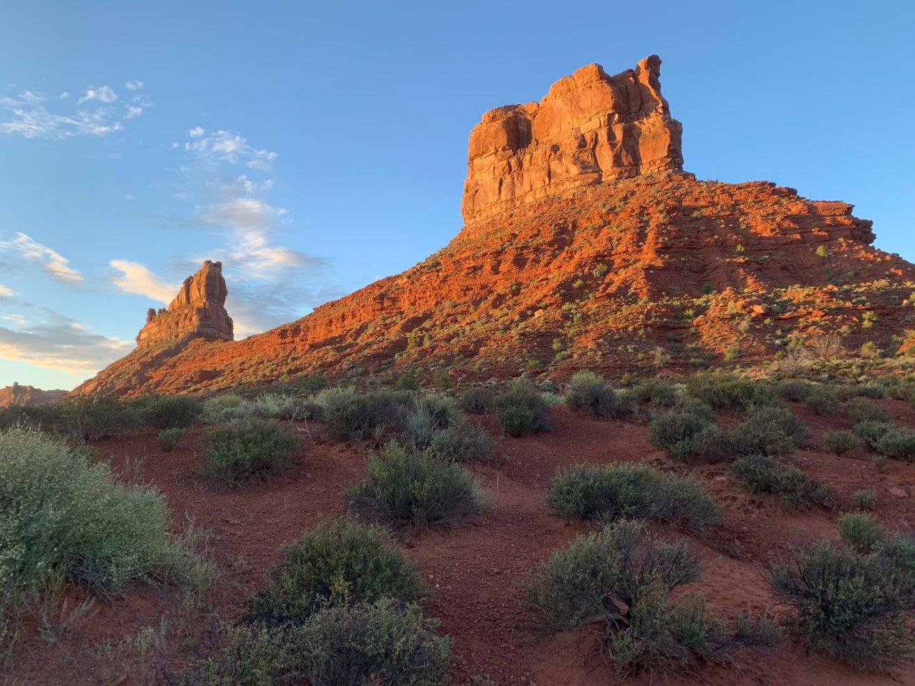 a huge red rock tower sticks up on the horizon with a characteristic utah view