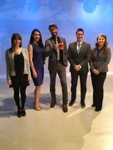 Five students pose on news set