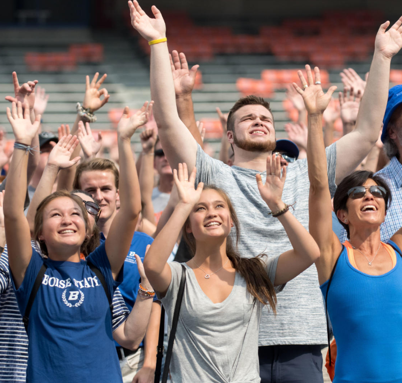 Students and parents raising their arms and looking up