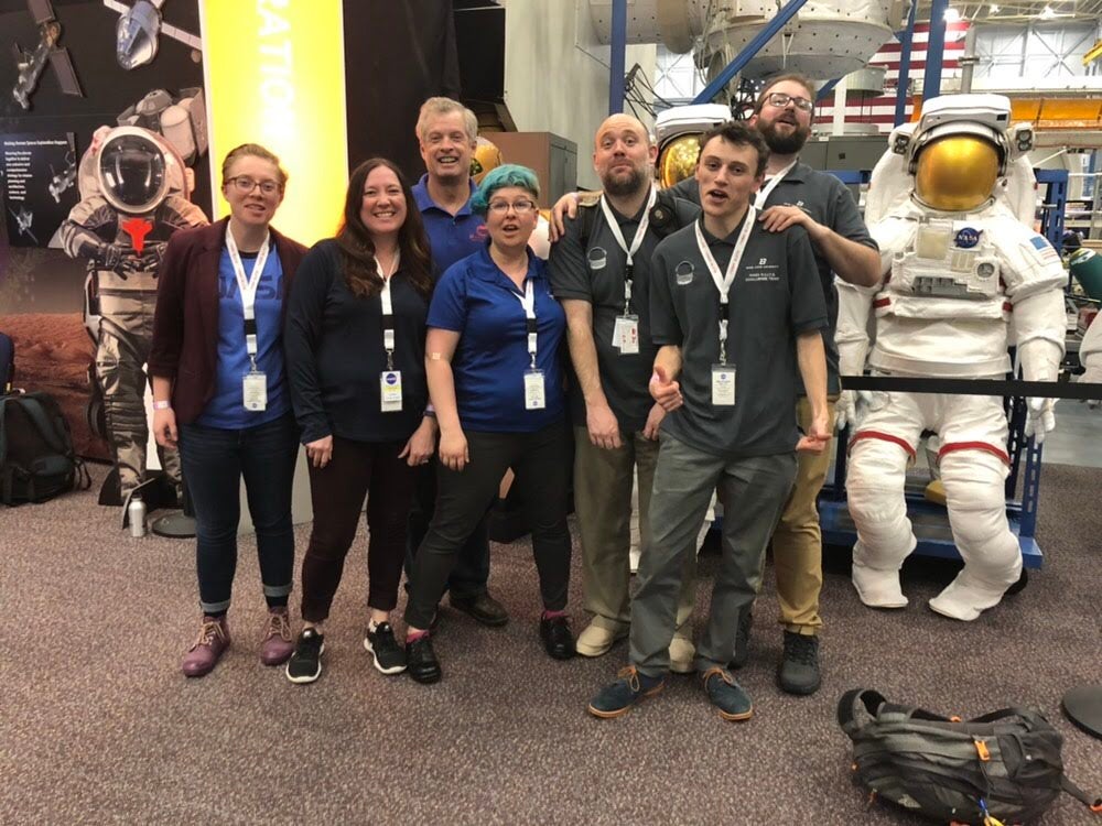 NASA Team inside Johnson Space Center, smiling in front of the camera
