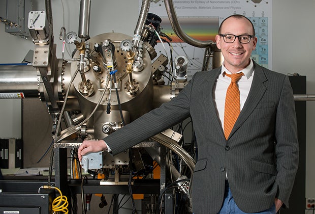 Paul Simmonds stands next to molecular beam epitaxy machine