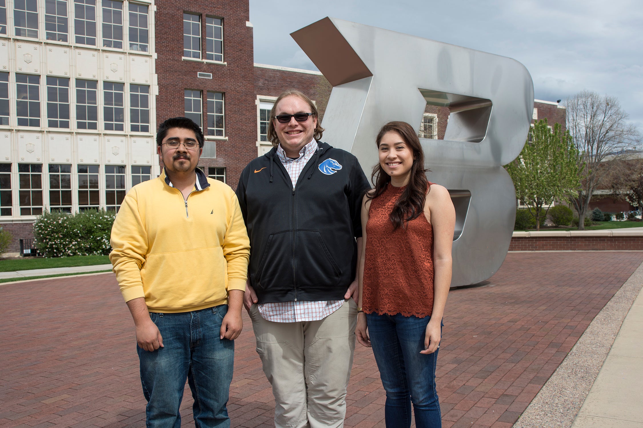 Three students pose in front of the B