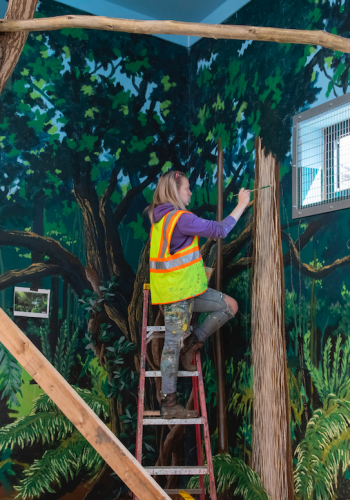 A student paints a wooded scene at Zoo Boise