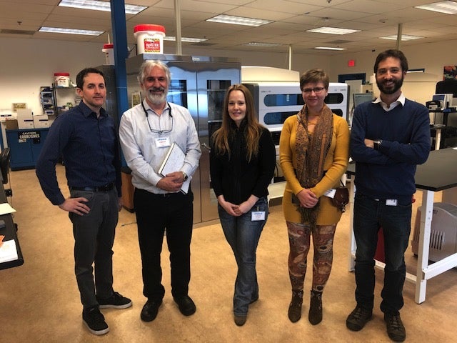 Five people stand in a lab and smile like they're having fun!