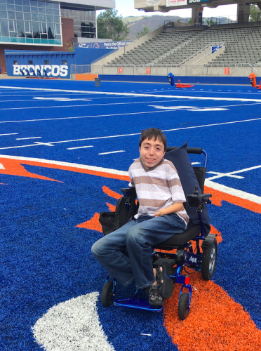 A student poses on the blue turf