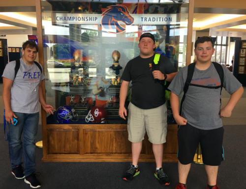 Three students pose by a Bronco trophy case