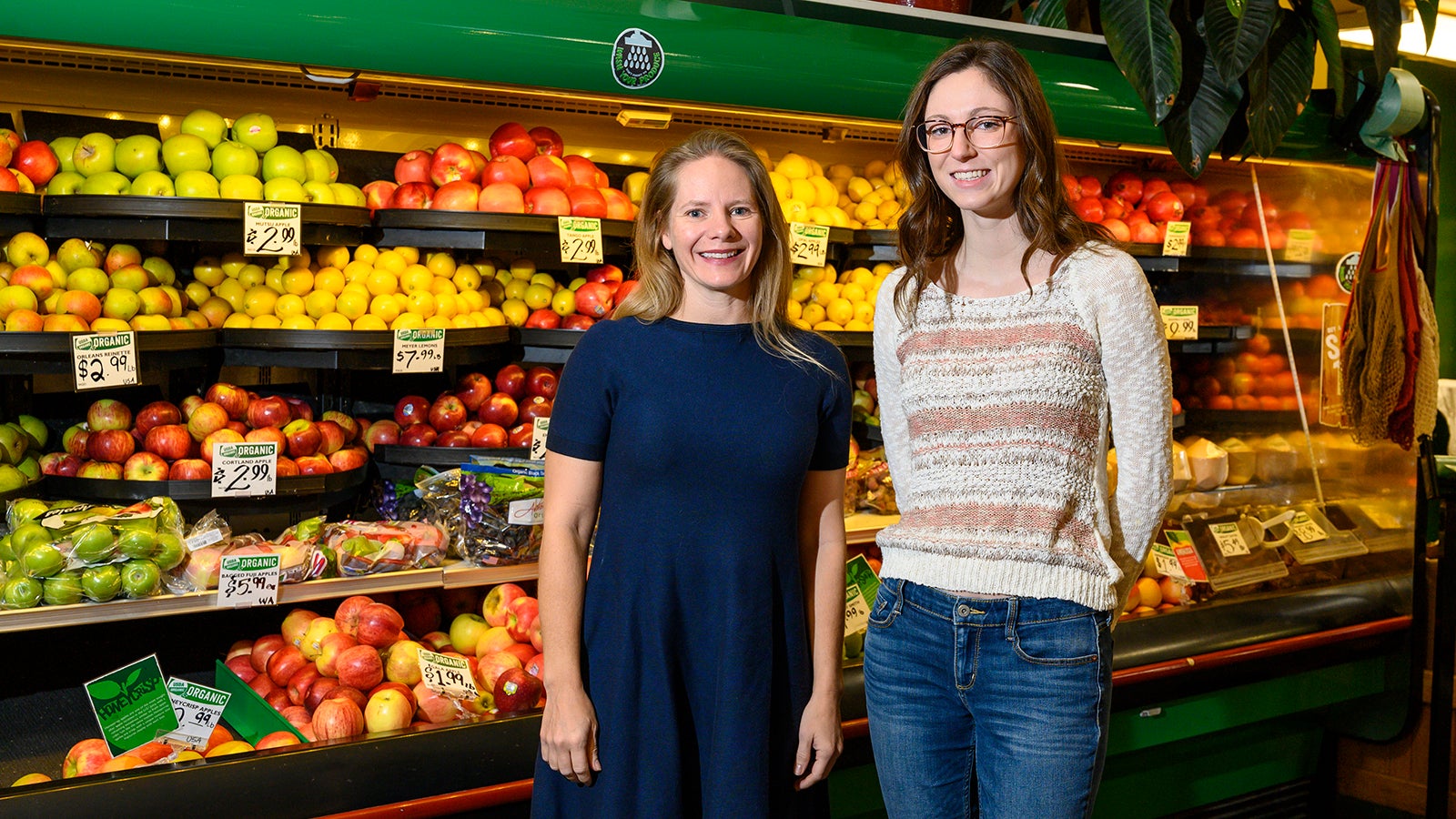 Two women stand in front of produce