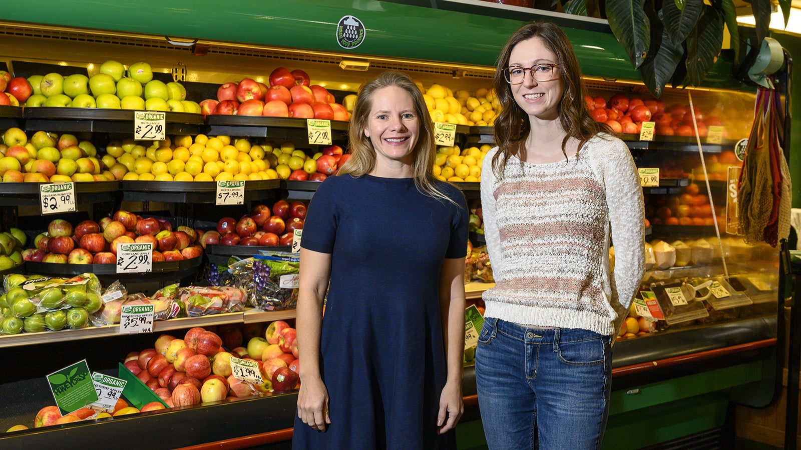 Two women stand in front of produce